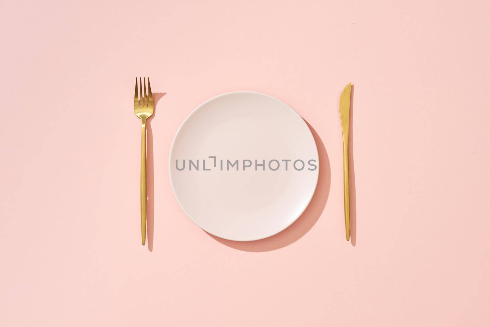 Knife, pastel pink plate and fork on pink background by makidotvn