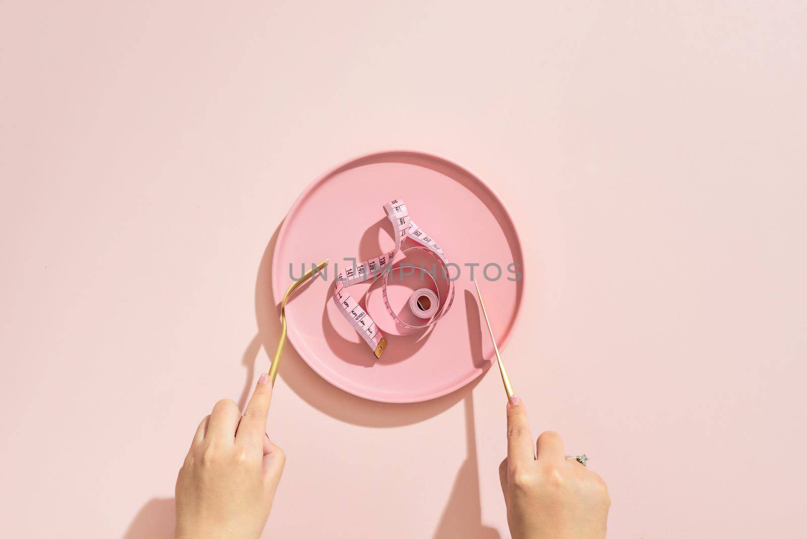 Empty plate with measuring tape, knife and fork. Diet food on a color table