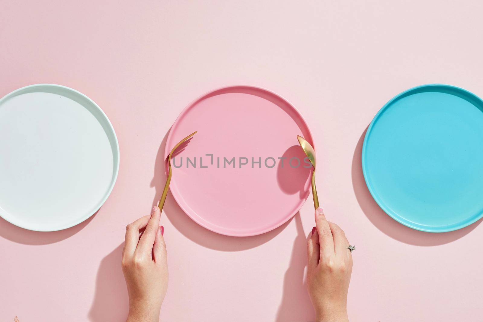 Restaurant and Food theme: the human hand show gesture on an empty three color plates on a pink background