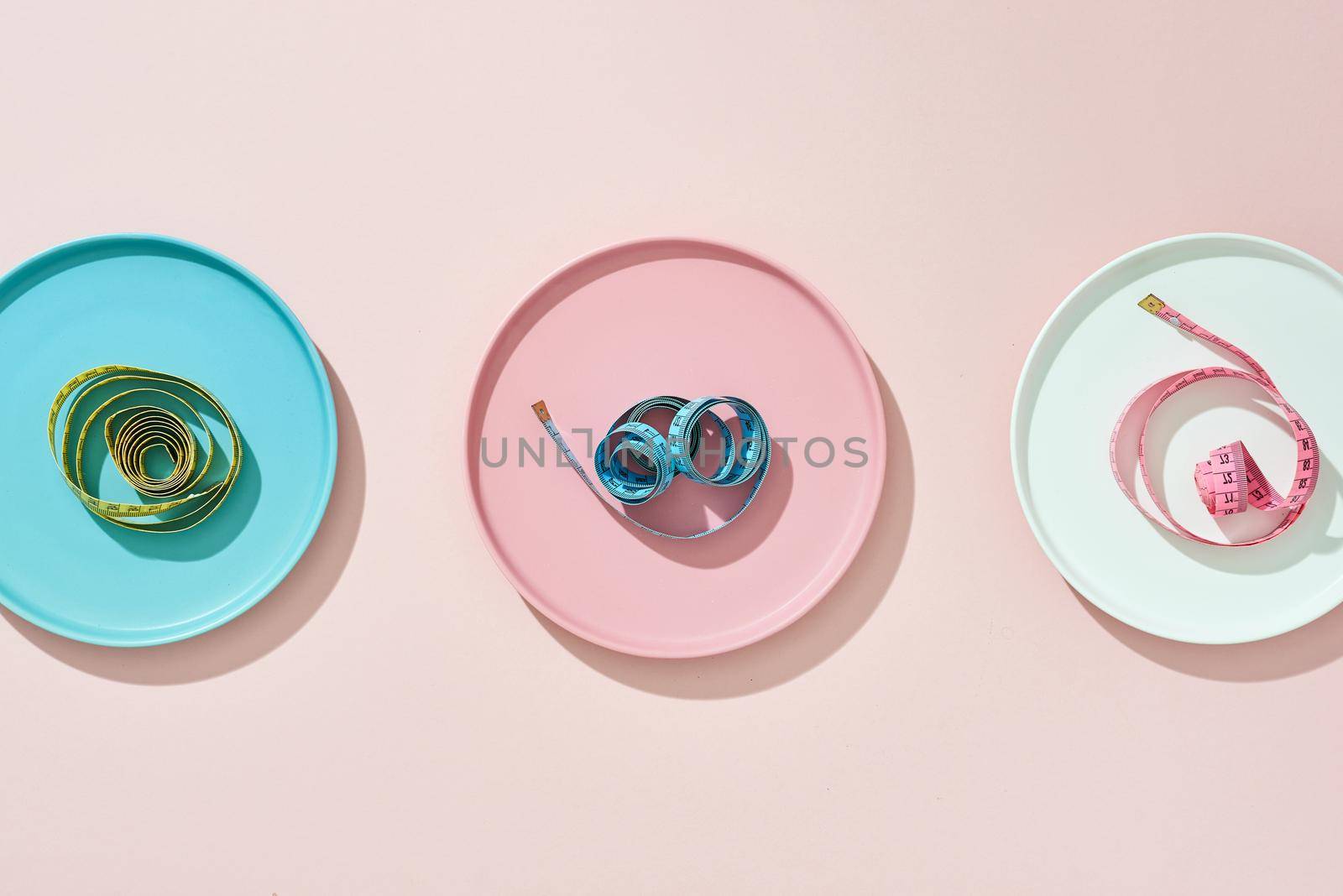 three plate with measuring tape on color background. Diet concept by makidotvn