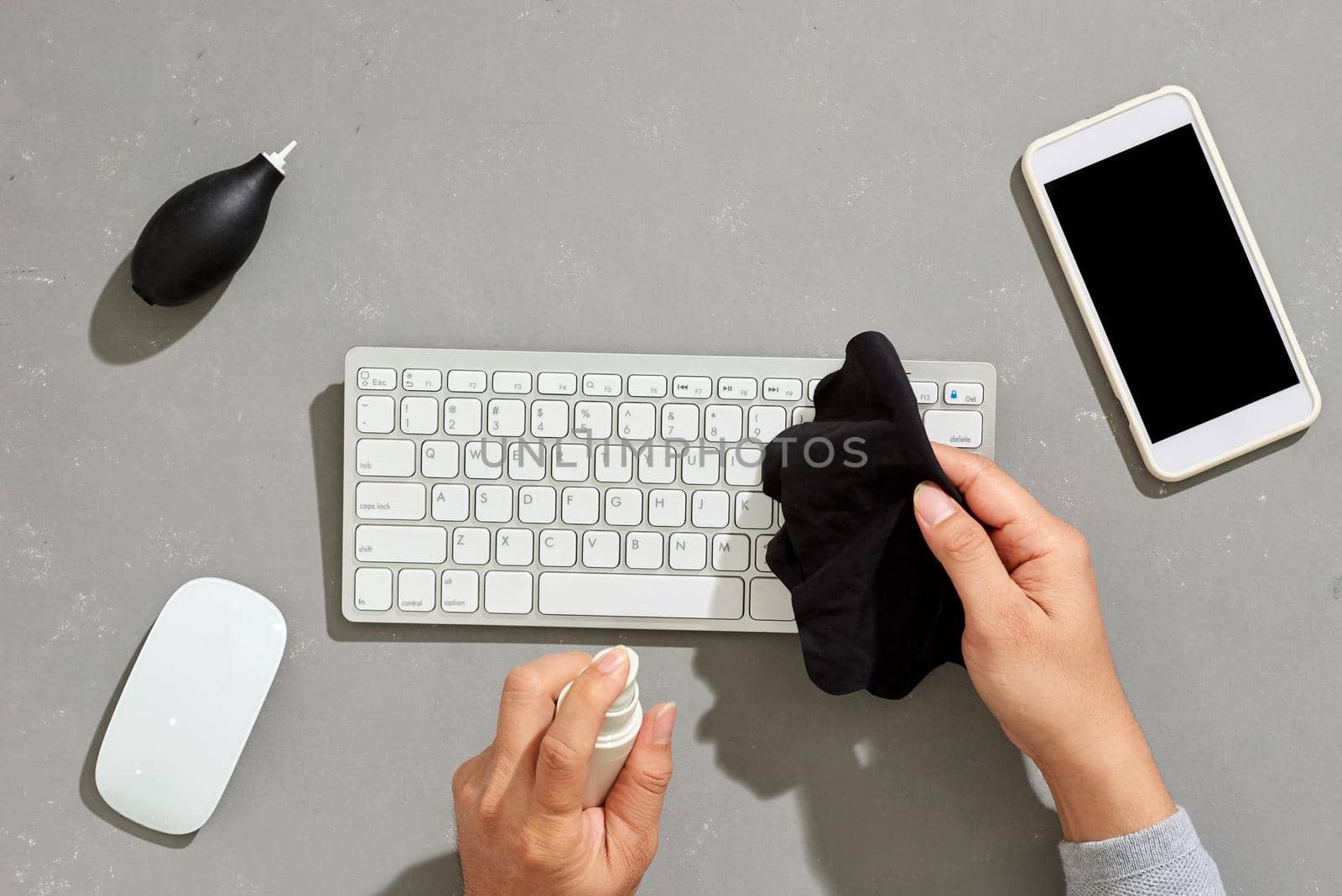 Top view close up of young man wiping keyboard with sanitizing wipes while working at desk