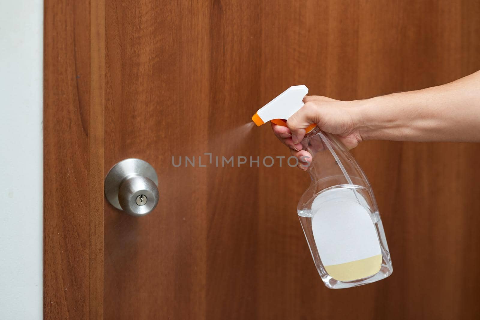 Hand hold bottle alcohol spraying disinfecting door. by makidotvn