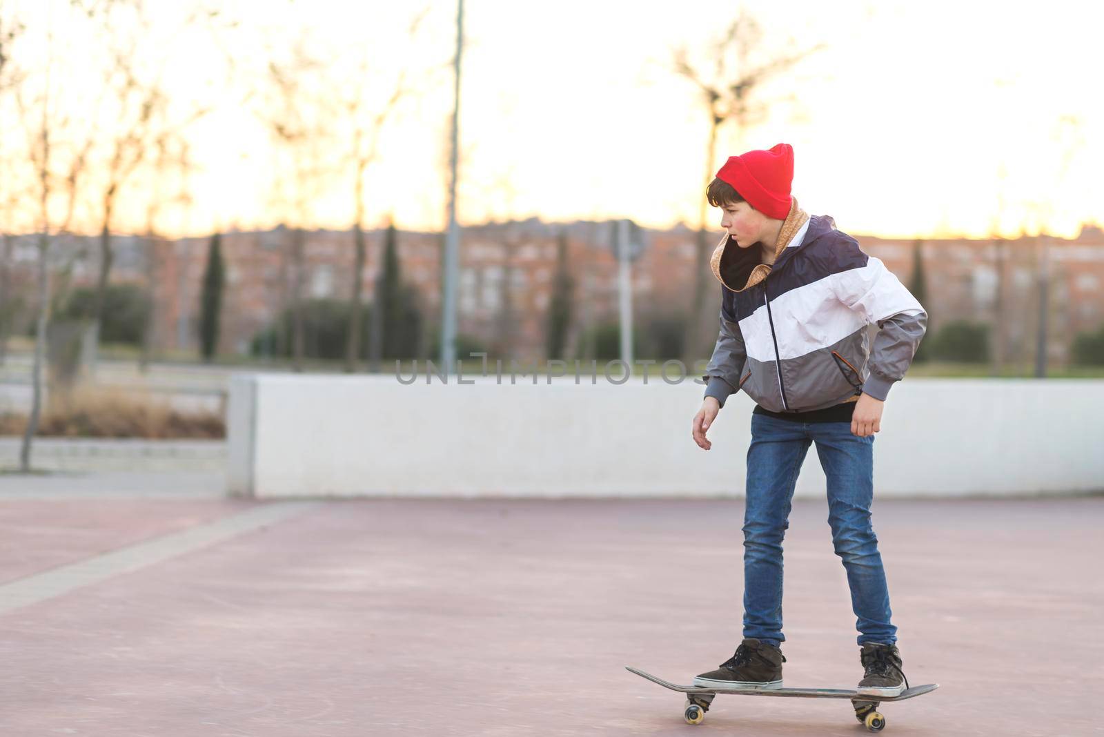 Side view of a teenager skateboarder boy with a skateboard on asphalt playground doing tricks. by raferto1973