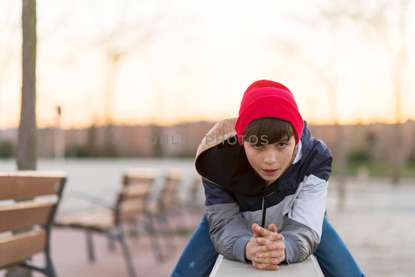 Stylish teenager sitting on a fence in a city park