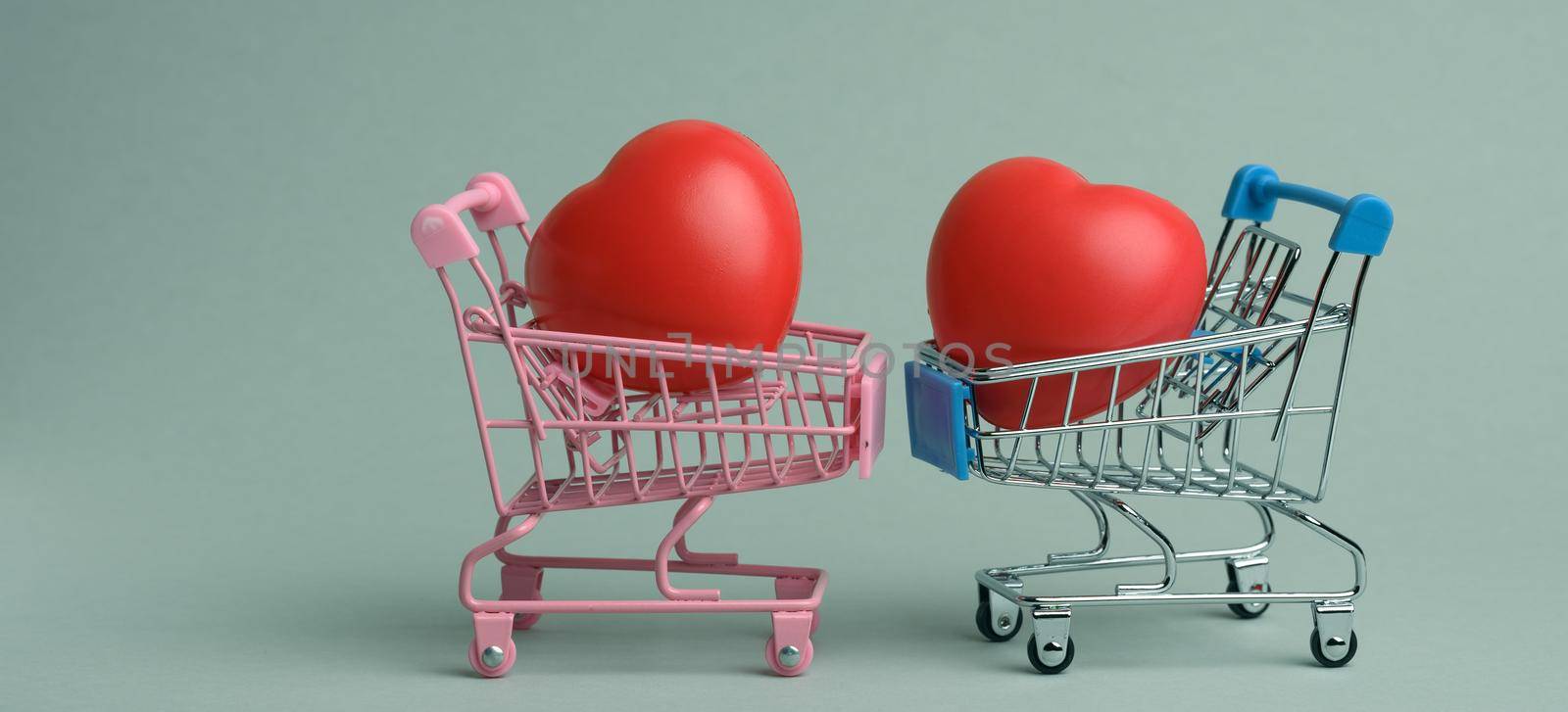 red heart in a miniature metal trolley from the store on a gray background. Organ donation, transplant concept