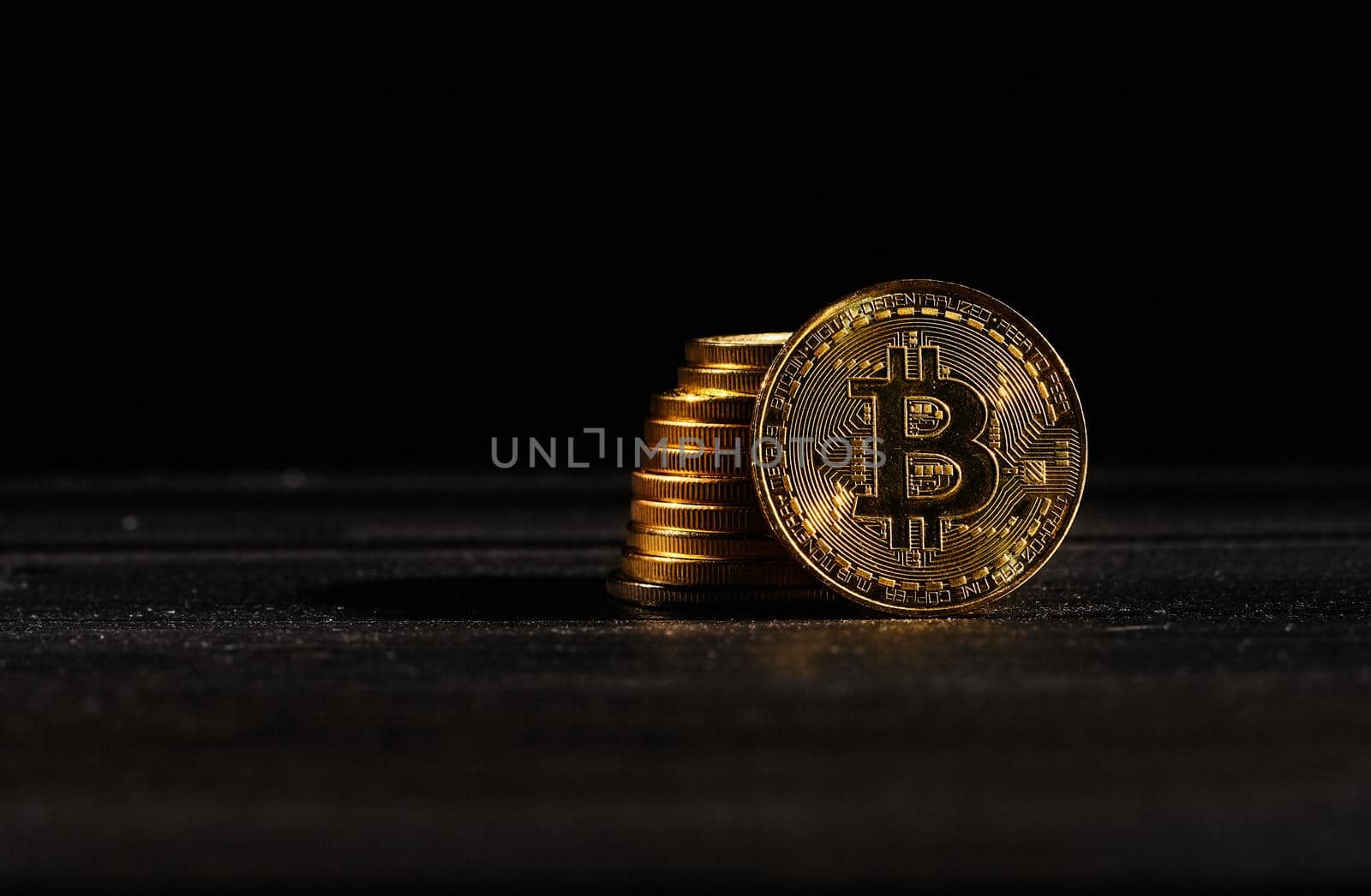 Leader in cryptocurrency bitcoin BTC on a top of coins against black wooden surface. Closeup golden coin with bitcoin logo. Stack of decentralized digital currency. Crypto payment. Electronic money
