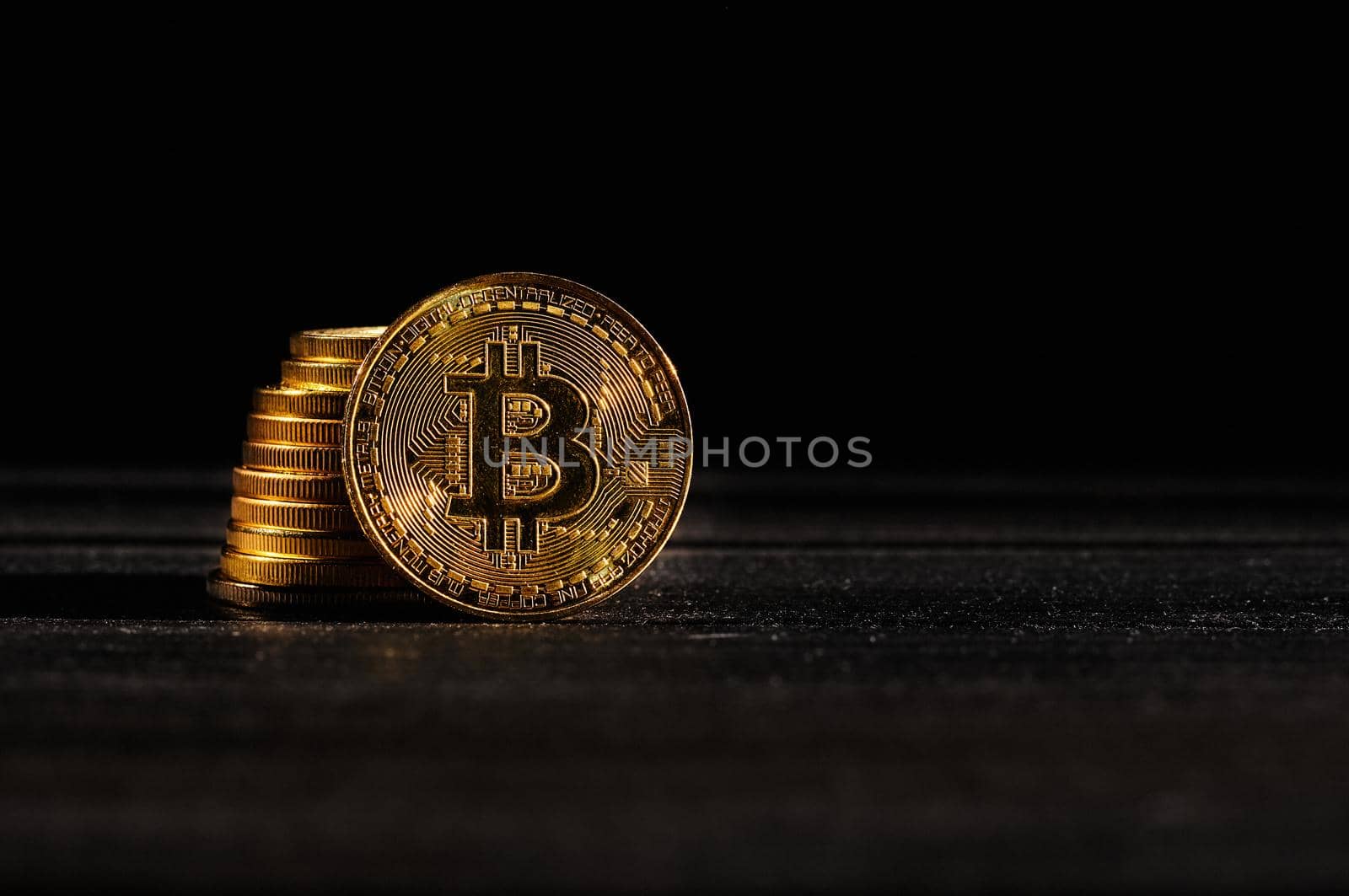 Leader in cryptocurrency bitcoin BTC on a top of coins against black wooden surface. Closeup golden coin with bitcoin logo. Stack of decentralized digital currency. Crypto payment. Electronic money