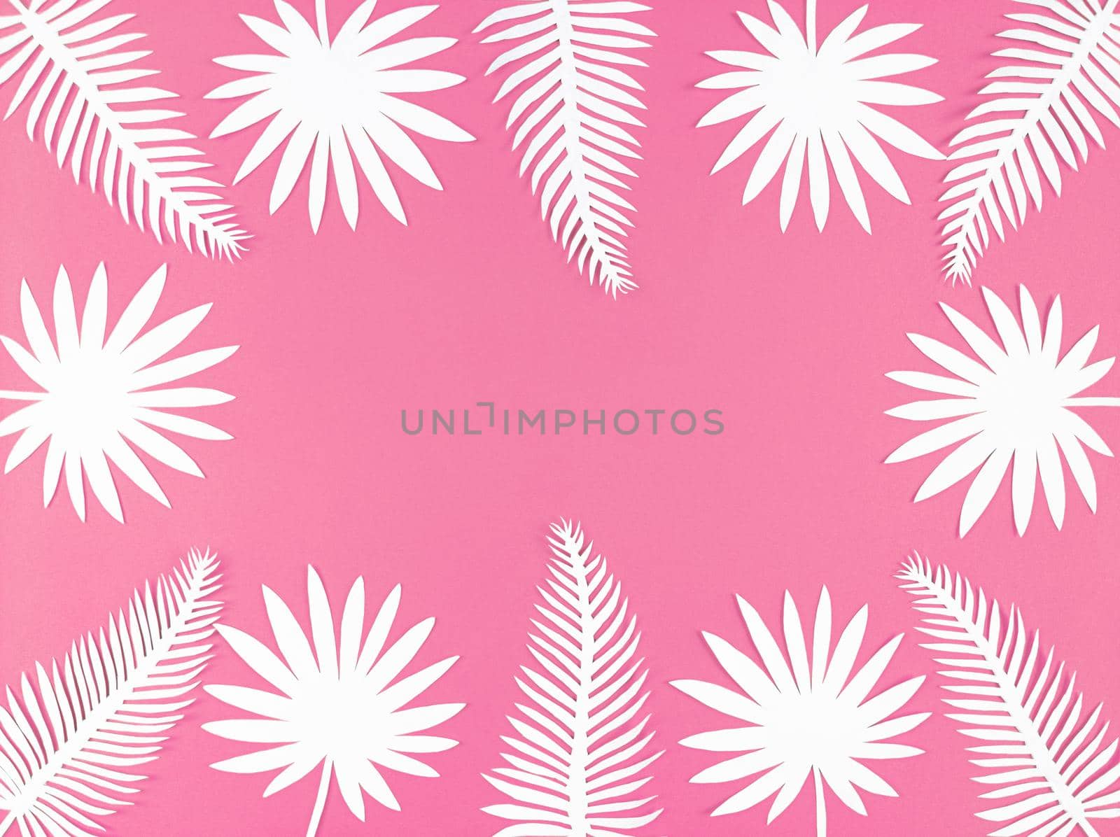 Tropical paper leaves on a pink background, flat lay with copy space.