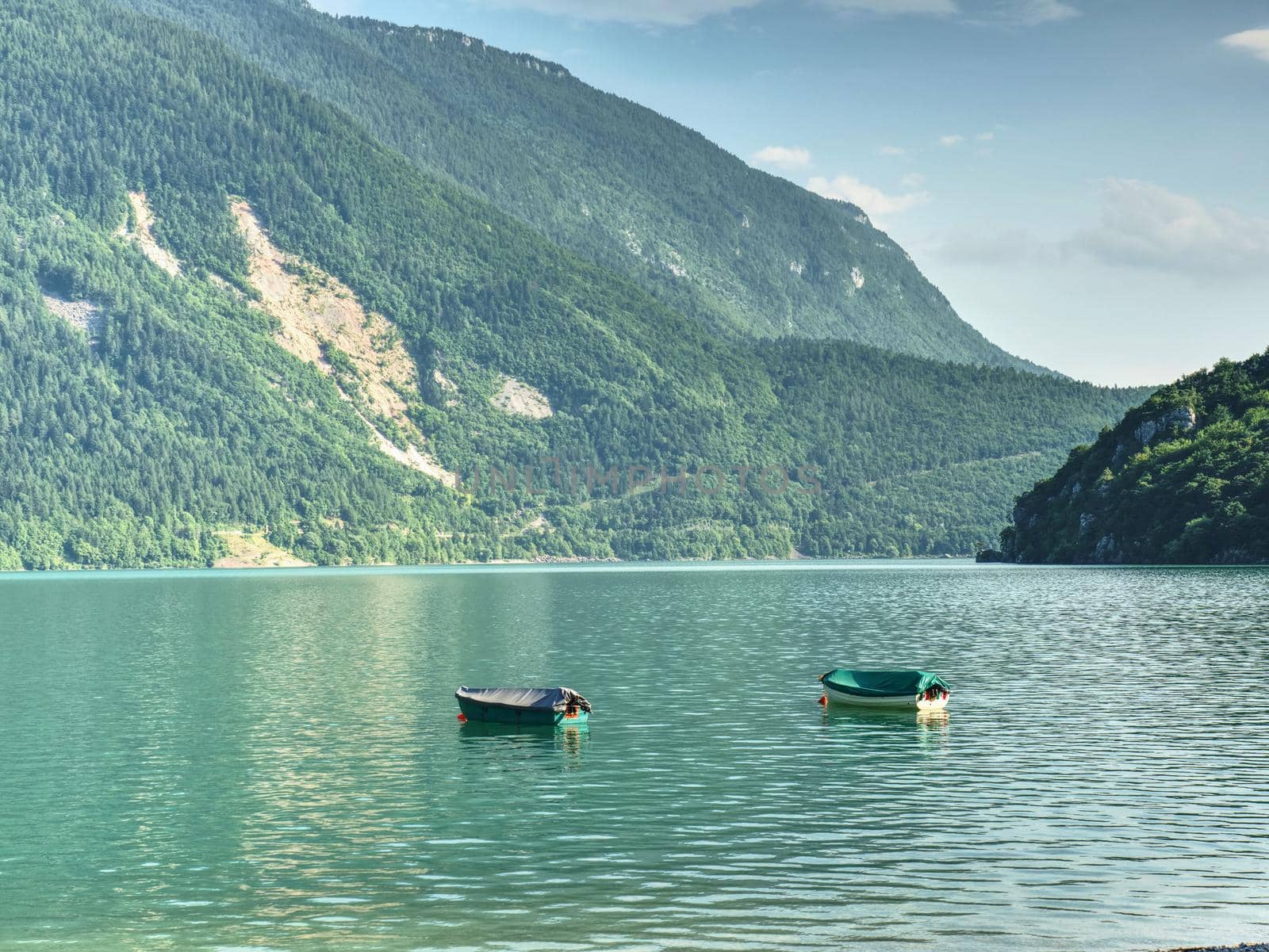 Beautiful high mountain lake with mountains around. The incredibly magic blue green lake with fishing boats or canoe