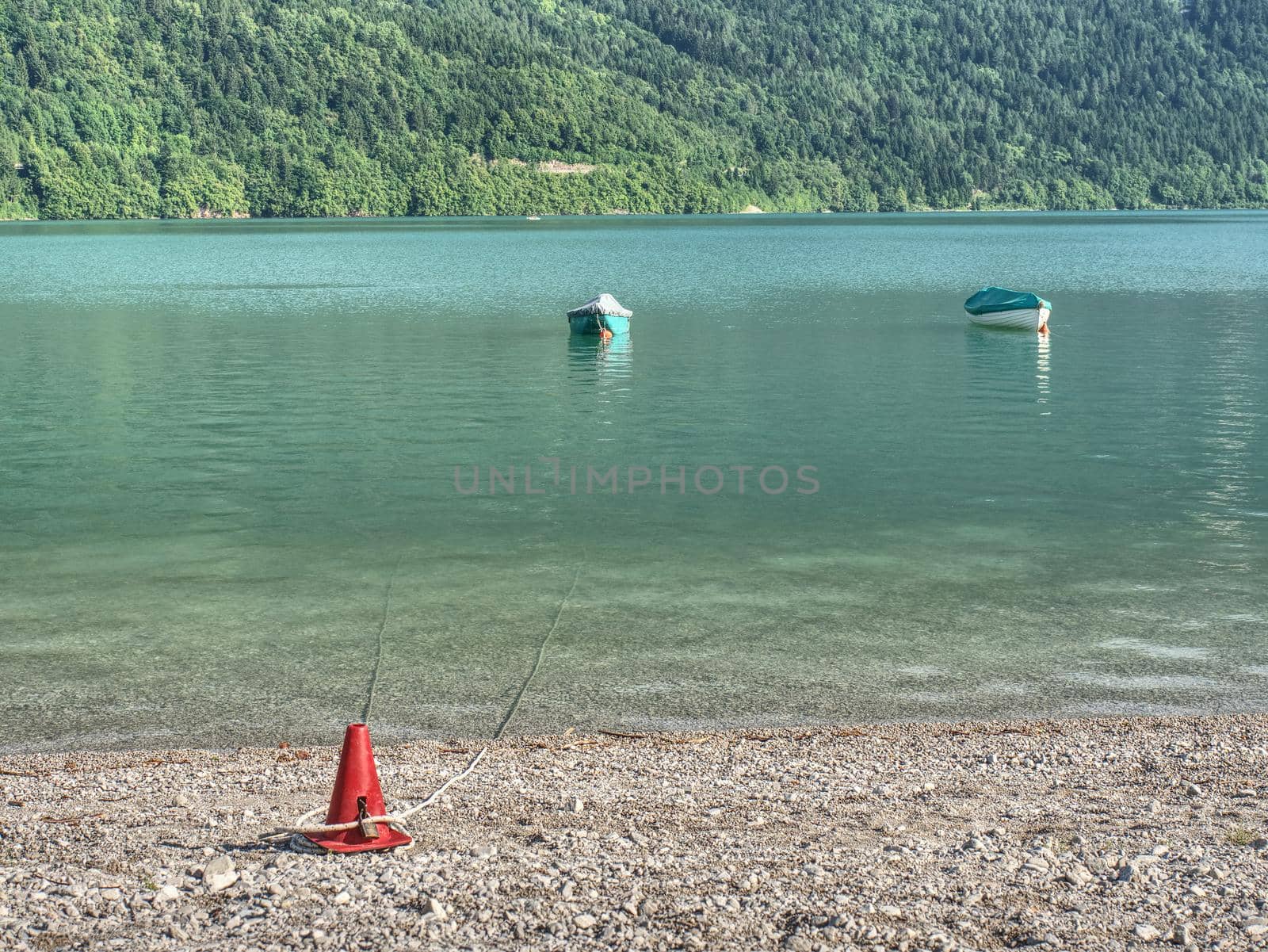 Beautiful high mountain lake with mountains around. The incredibly magic blue green lake with fishing boats or canoe