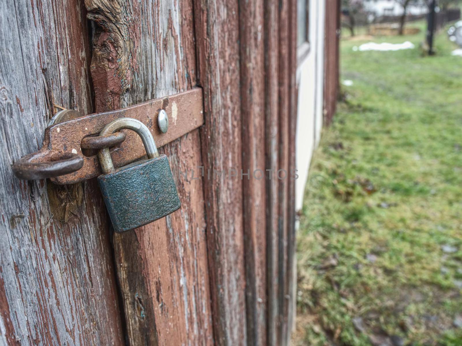 Old wooden door in the stone wall from medieval era. Vintage metal padlock on a wooden door.