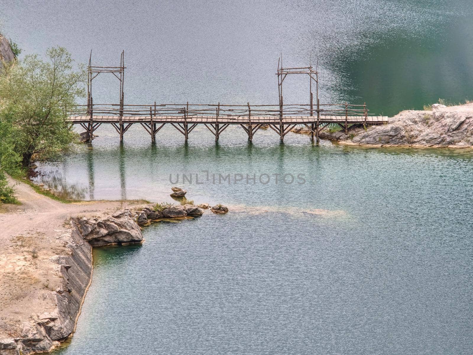 Green blue lake with wooden tourist path bridge above cold water. Hiking in the national park