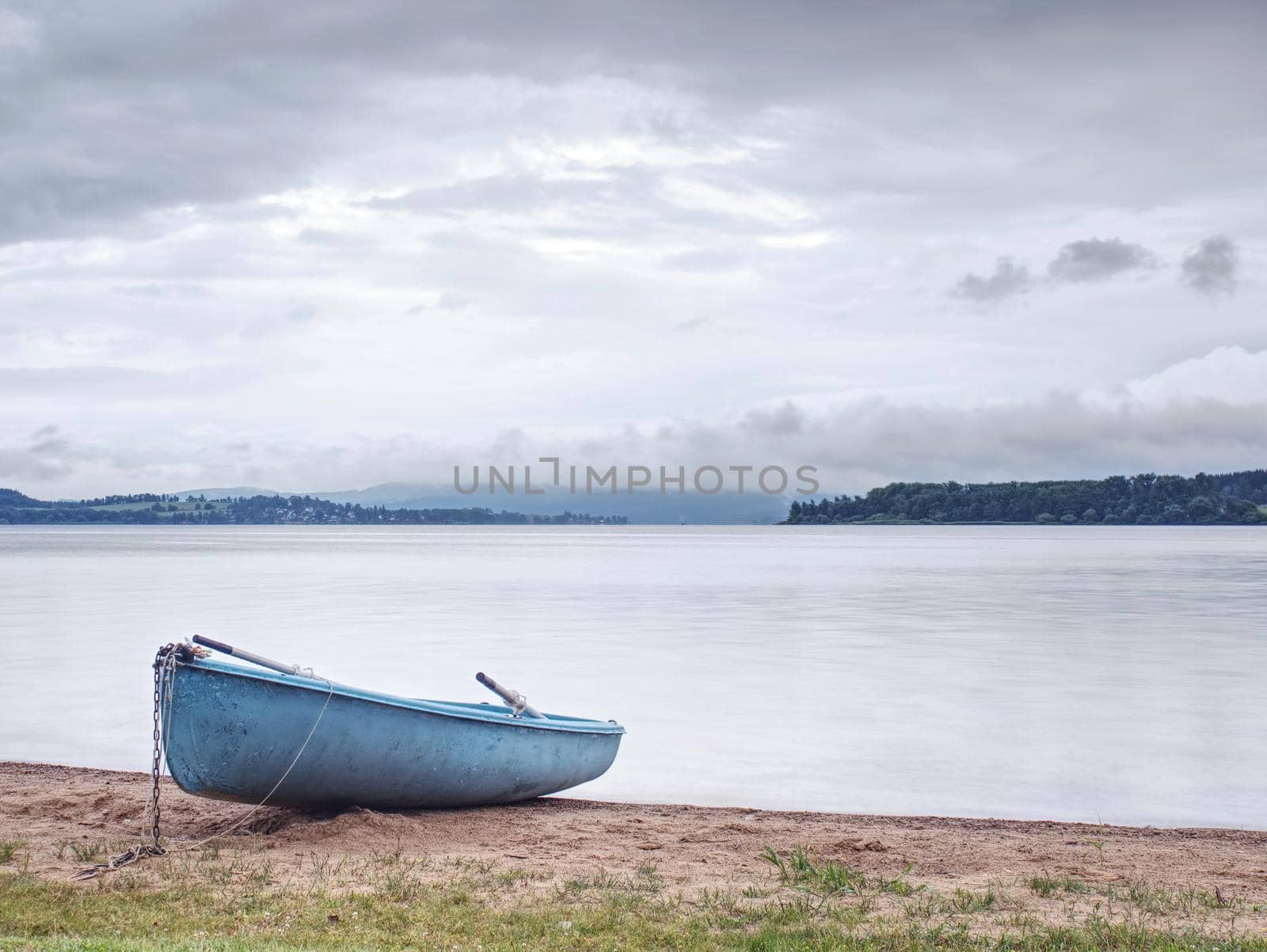 Boat anchored in calm bay. Touristic resort with nobody.  Calm water level, idilic walk at shore.