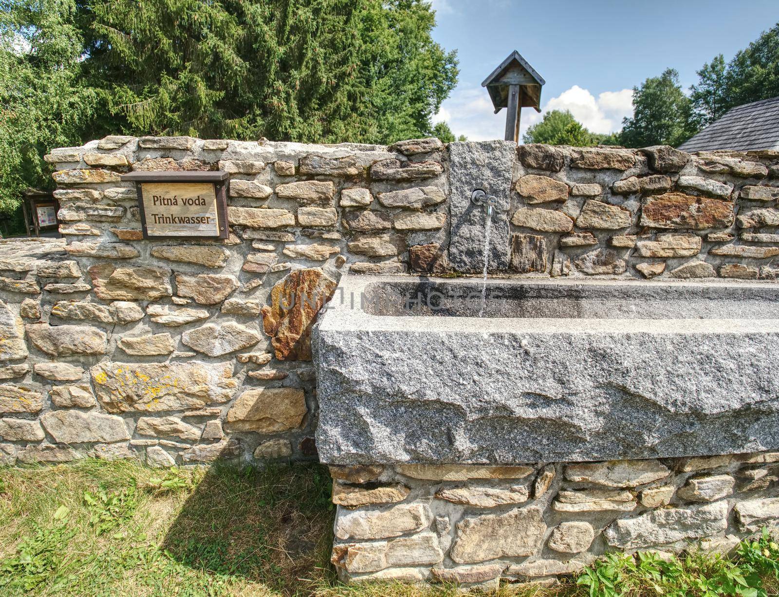 Mountain spring of pure, clear, fresh water with water tap trough in mountain village.