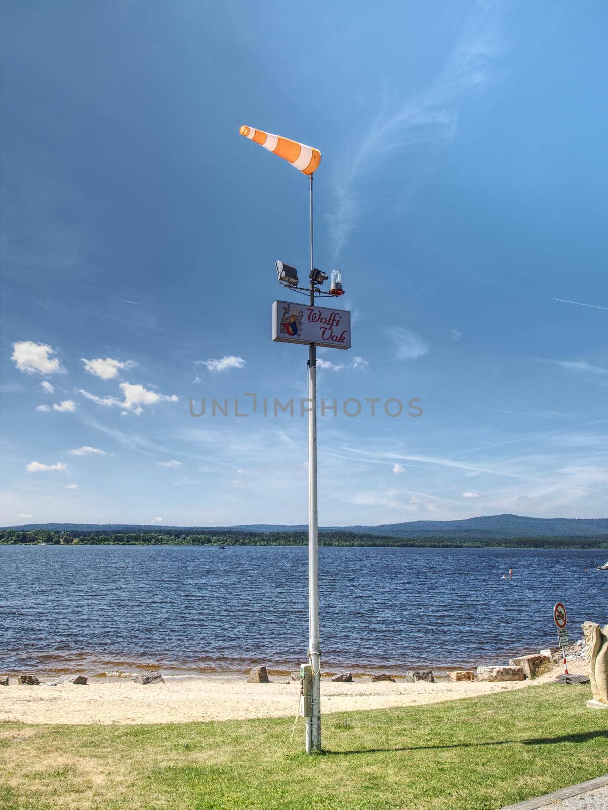 Ferry pier with windsock at the shore of Lipno lake, gentle wind.  16th of July 2019, Lipno lake Czech Republic