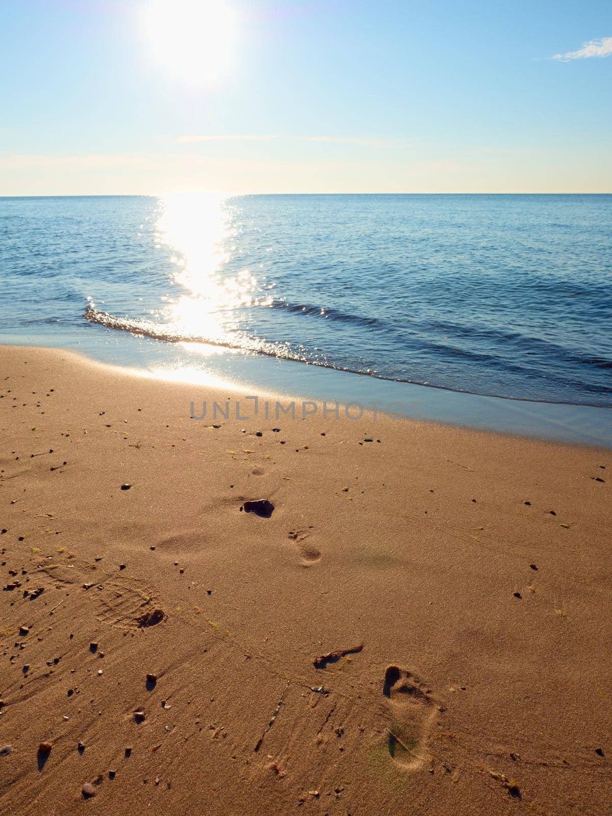 Footprints in beach sand. Traces on beach by smooth sea by rdonar2