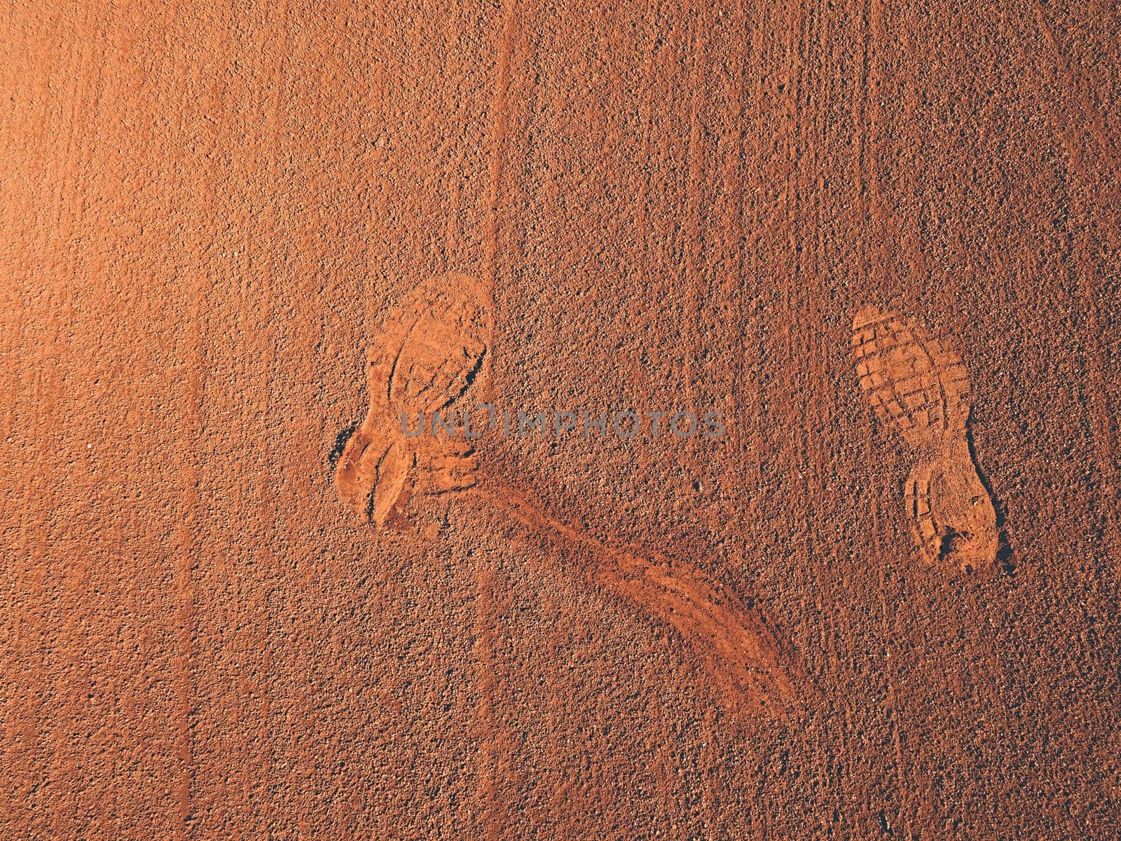 Detail with a sport shoe footprint on a tennis clay court. Dry light red crushed bricks surface on outdoor tennis ground
