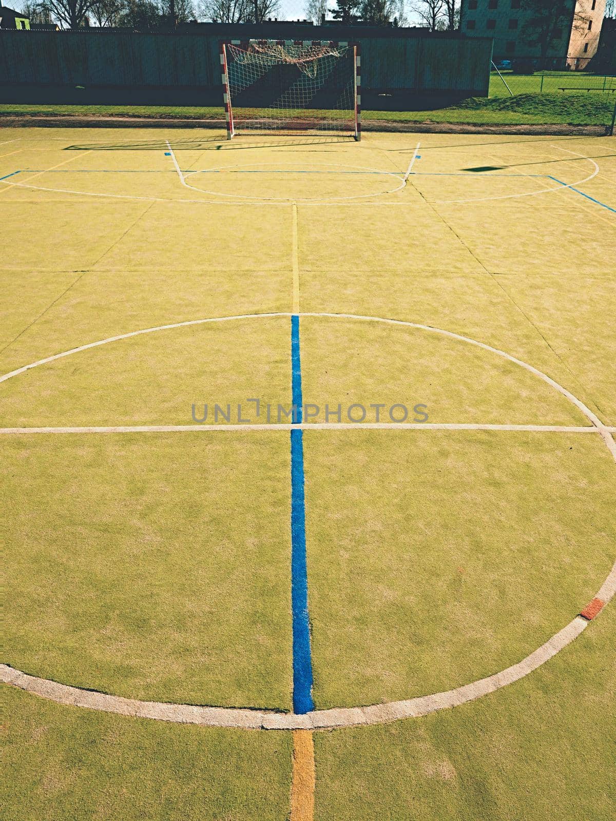 Circle in middle of court. Empty outdoor handball playground, plastic light green surface on ground and white blue bounds lines.