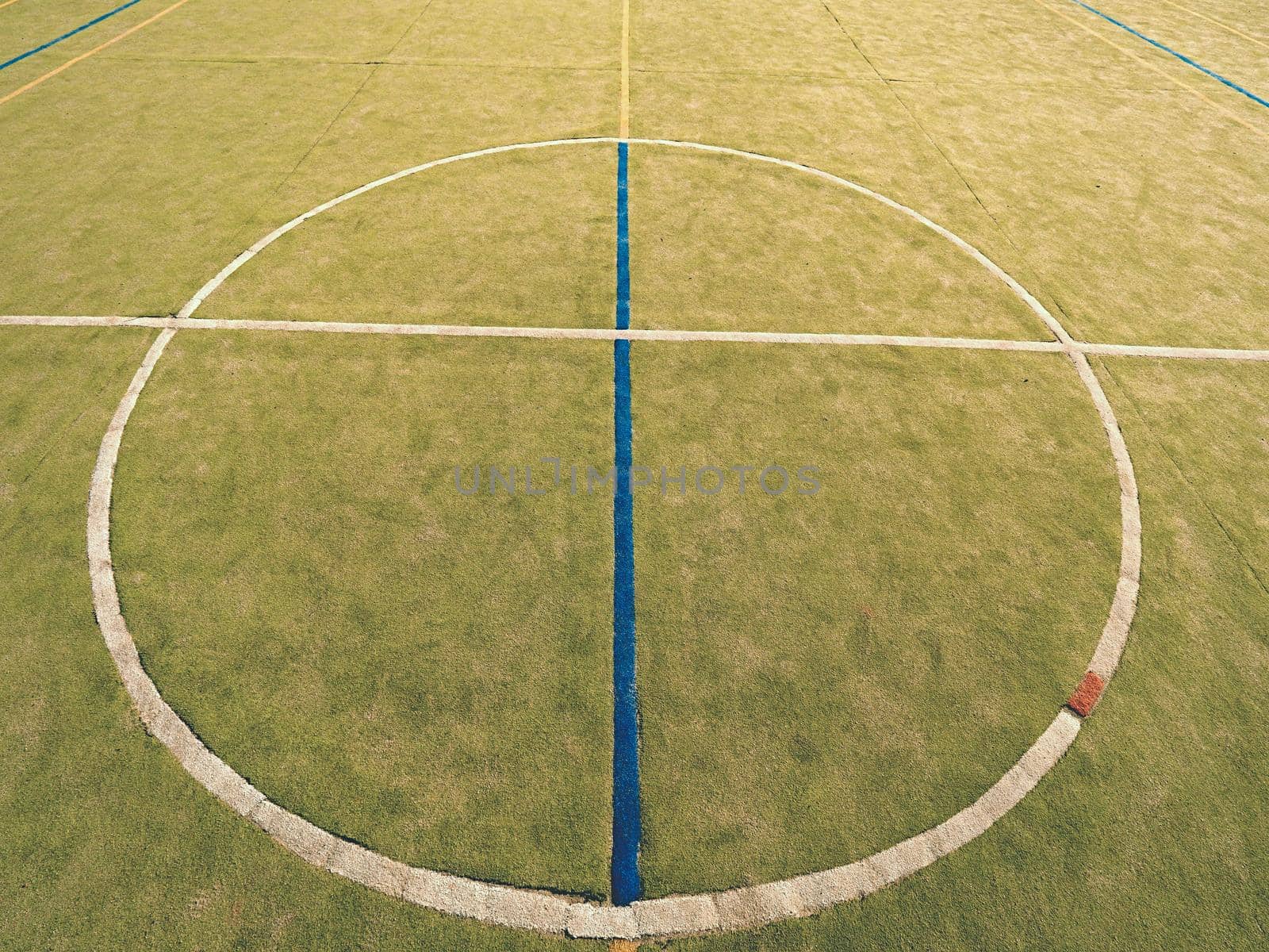 Circle in middle of court. Empty outdoor handball playground, plastic light green surface on ground and white blue bounds lines.