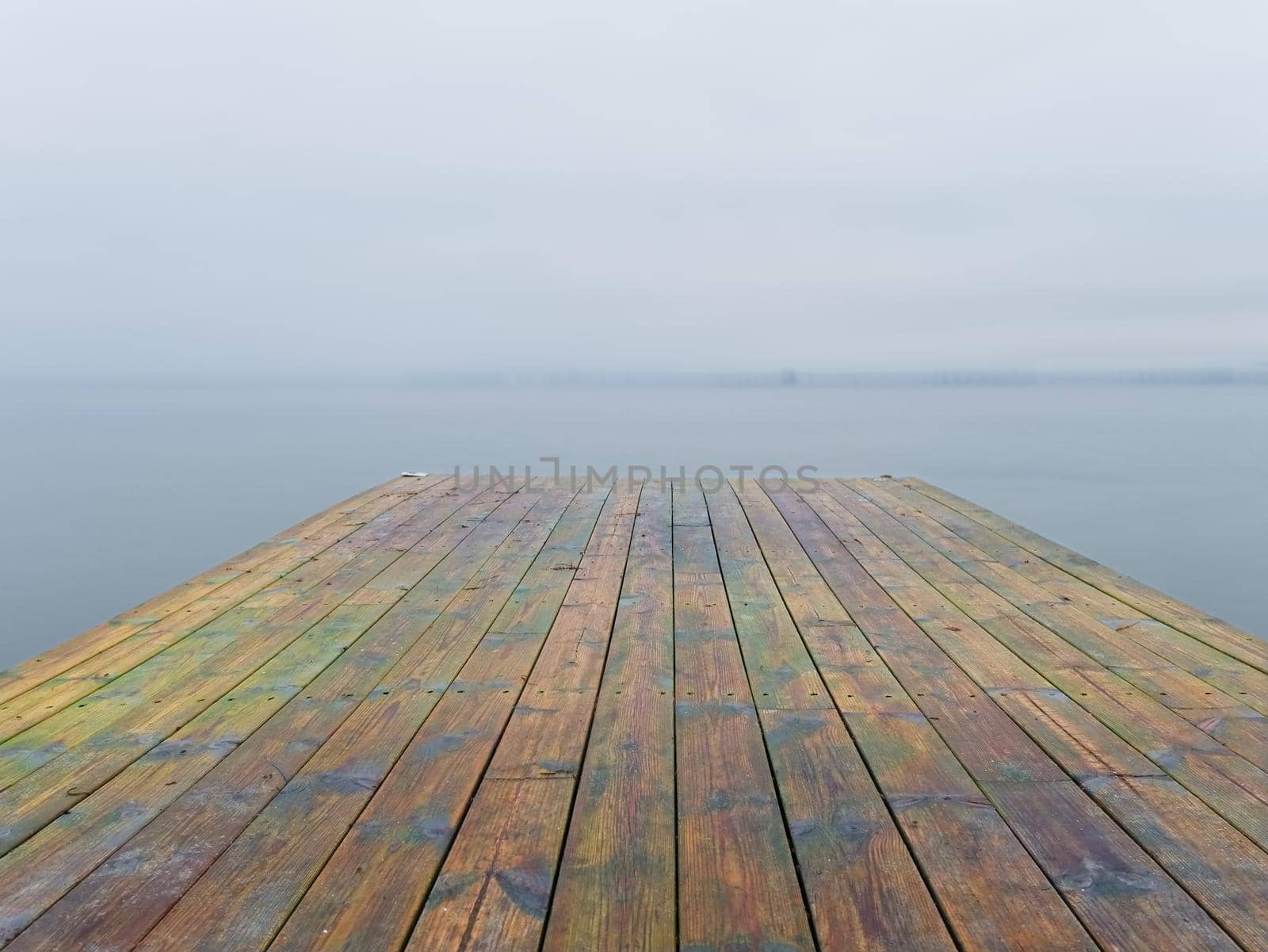 Abandoned wooden wharf mole in sea within sunrise. Gentle blue pink color of sky blurry waves on water level.