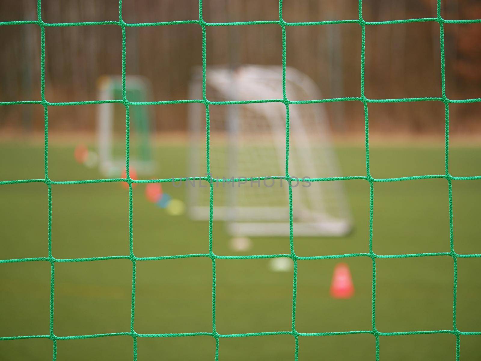 Soccer football net background over green grass and blurry stadium. Close up detail of a soccer net Footballsoccer field.  

