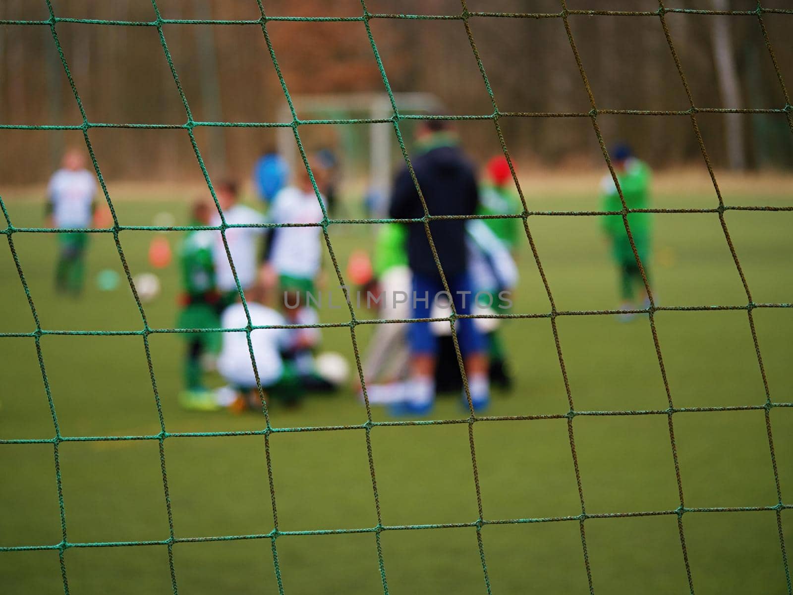 Football gate net. Soccer gate net. In blurry background stand players. Training of junior team. 