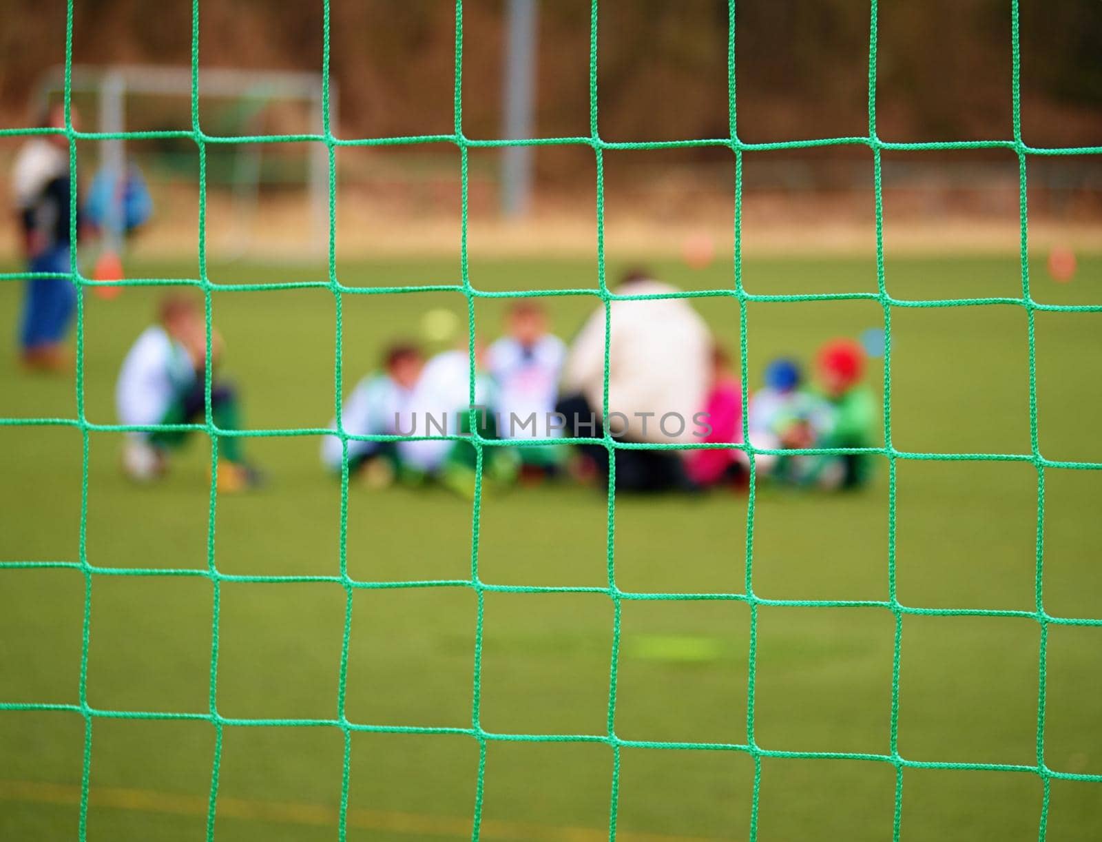 Football gate net. Soccer gate net. In blurry background stand players. Training of junior team. 