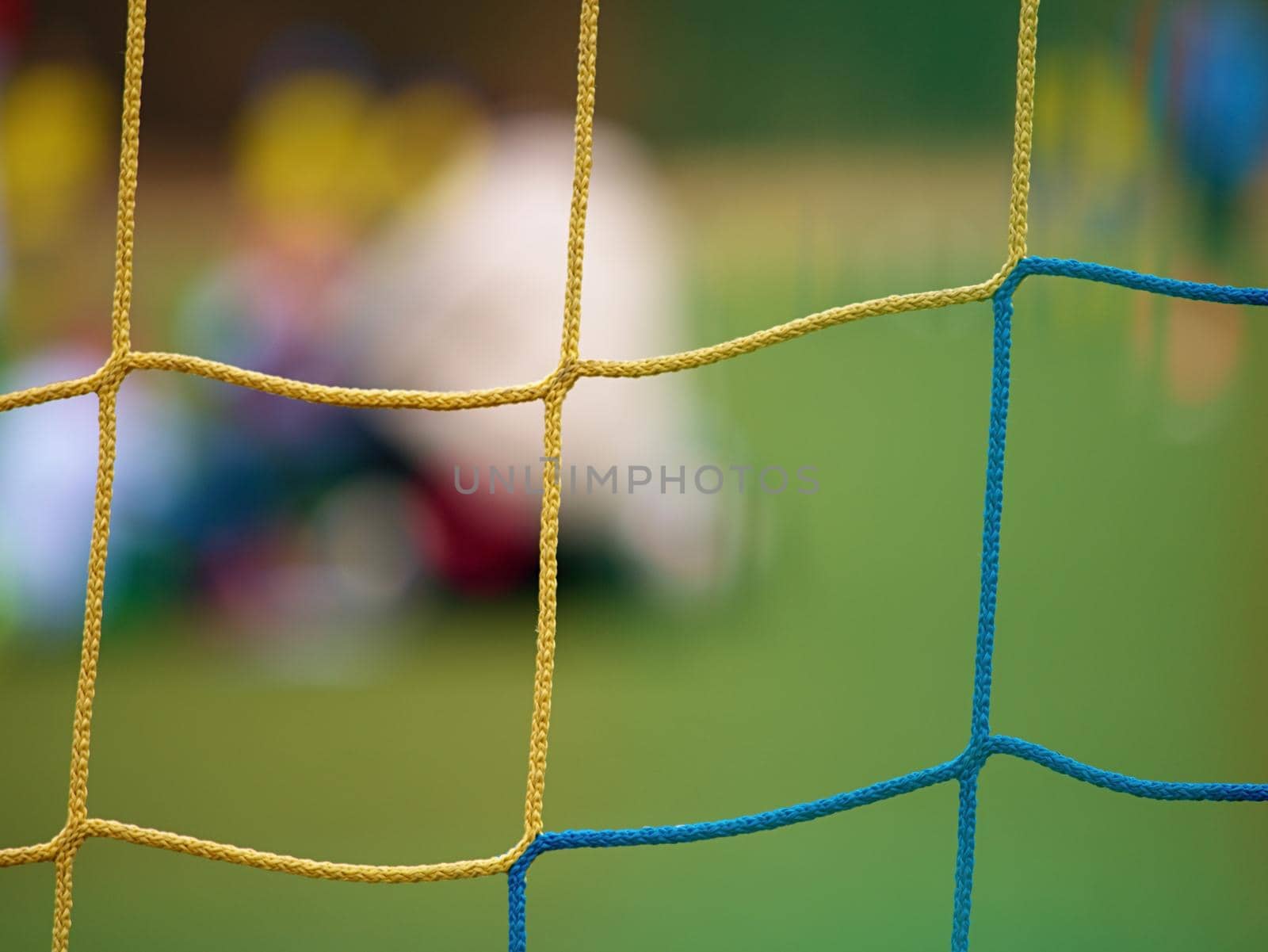 Football player stands against goal with net and stadium. Football gate net. Soccer gate net.  In blurry background stand people.