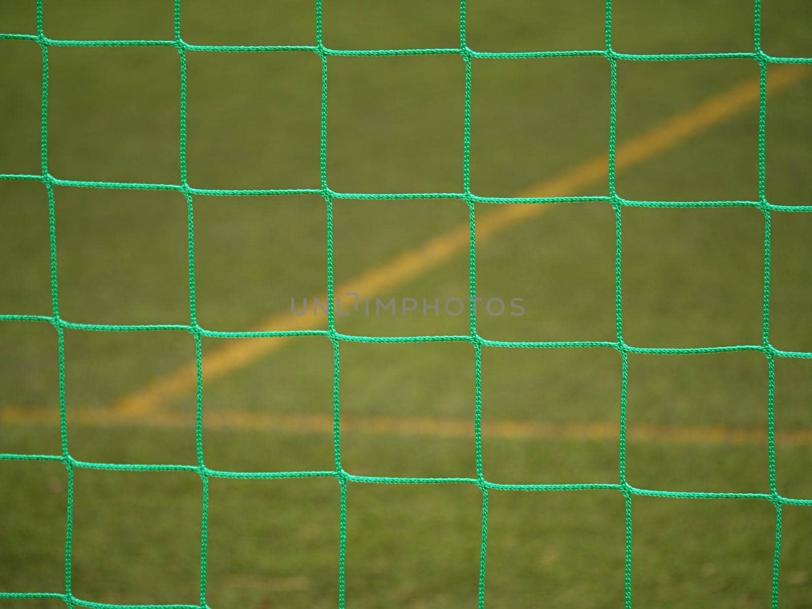 Detail of a soccer net against green grass on stadium. Selective focus with detailed knots
