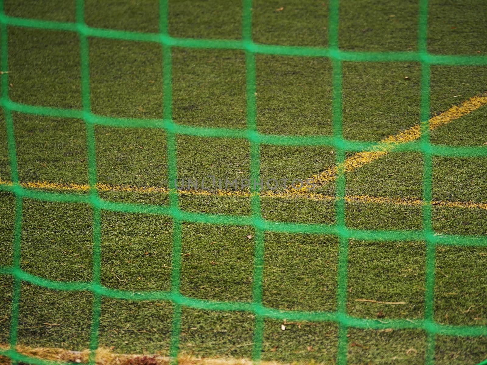 Close up detail of a soccer net against green grass on a cloudy day. Selective focus