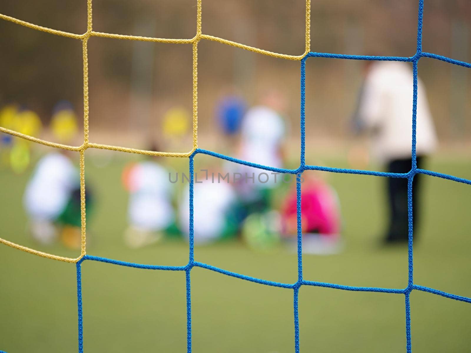 Football gate net. Soccer gate net. In blurry background stand players. Training of junior team. 