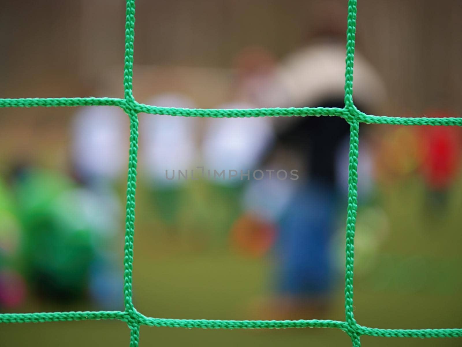 Football player stands against goal with net and stadium. Football gate net. Soccer gate net.  In blurry background stand people.