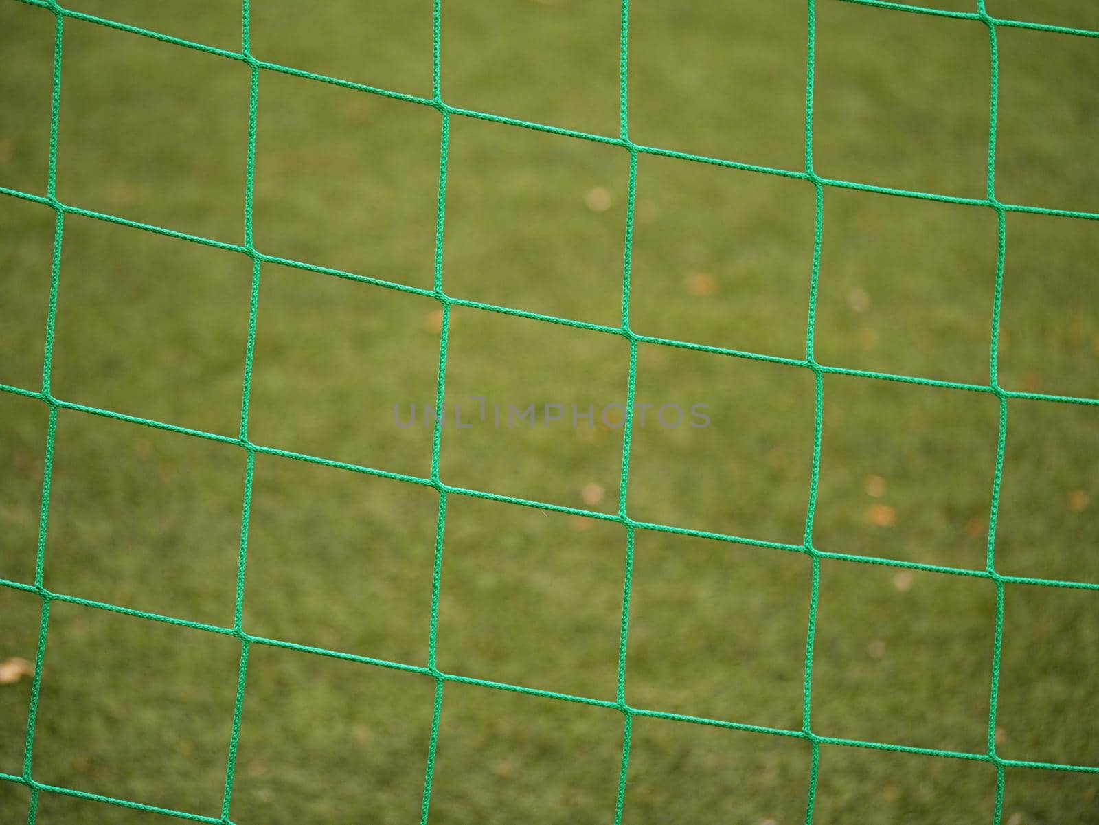 Close up detail of a soccer net against green grass on a cloudy day. Selective focus