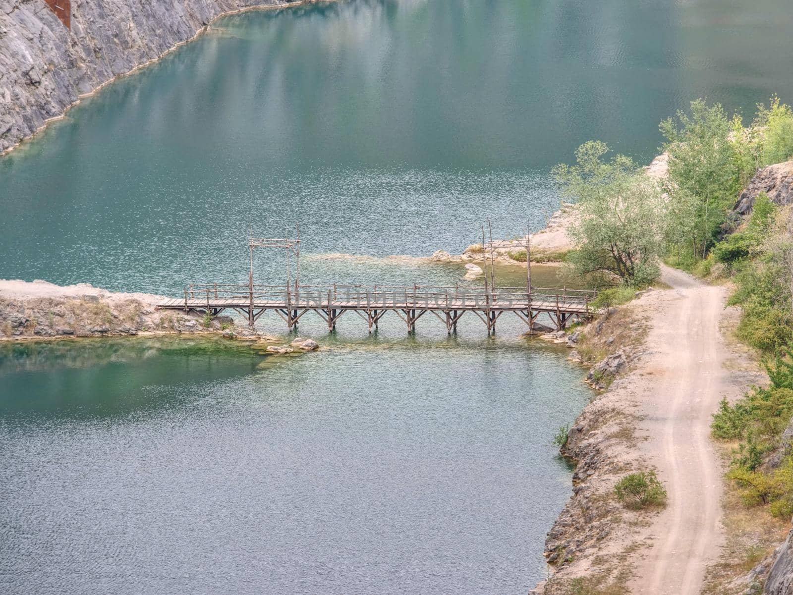 Green blue lake with wooden tourist path bridge above cold water. Hiking in the national park