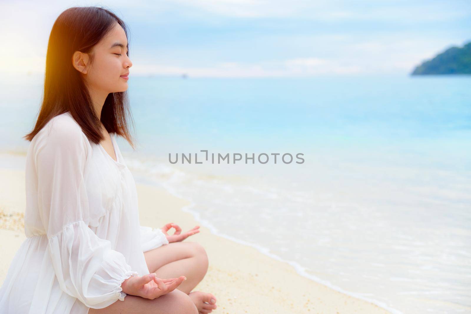 Asian young woman practice yoga on the beach by Yongkiet