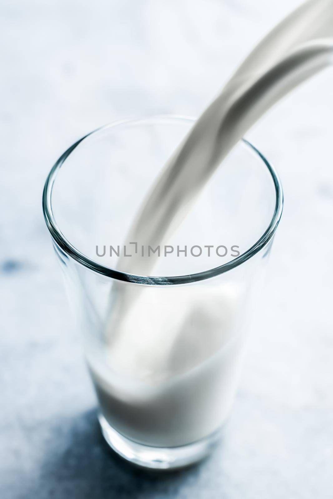 Dairy, healthy nutrition and breakfast concept - World Milk Day, pouring into glass on marble table