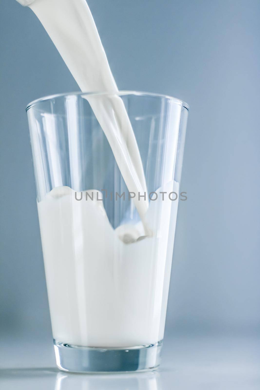 Dairy, healthy nutrition and breakfast concept - World Milk Day, pouring into glass on marble table