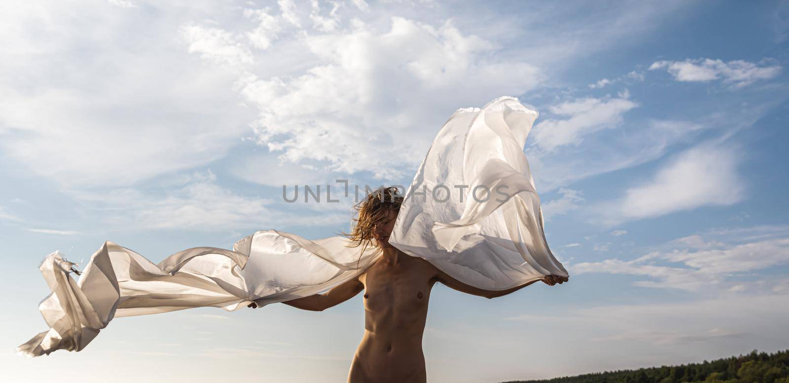 Naked girl outdoors enjoying nature on the seashore on a sunny day. Beautiful young nude woman against the sea. 