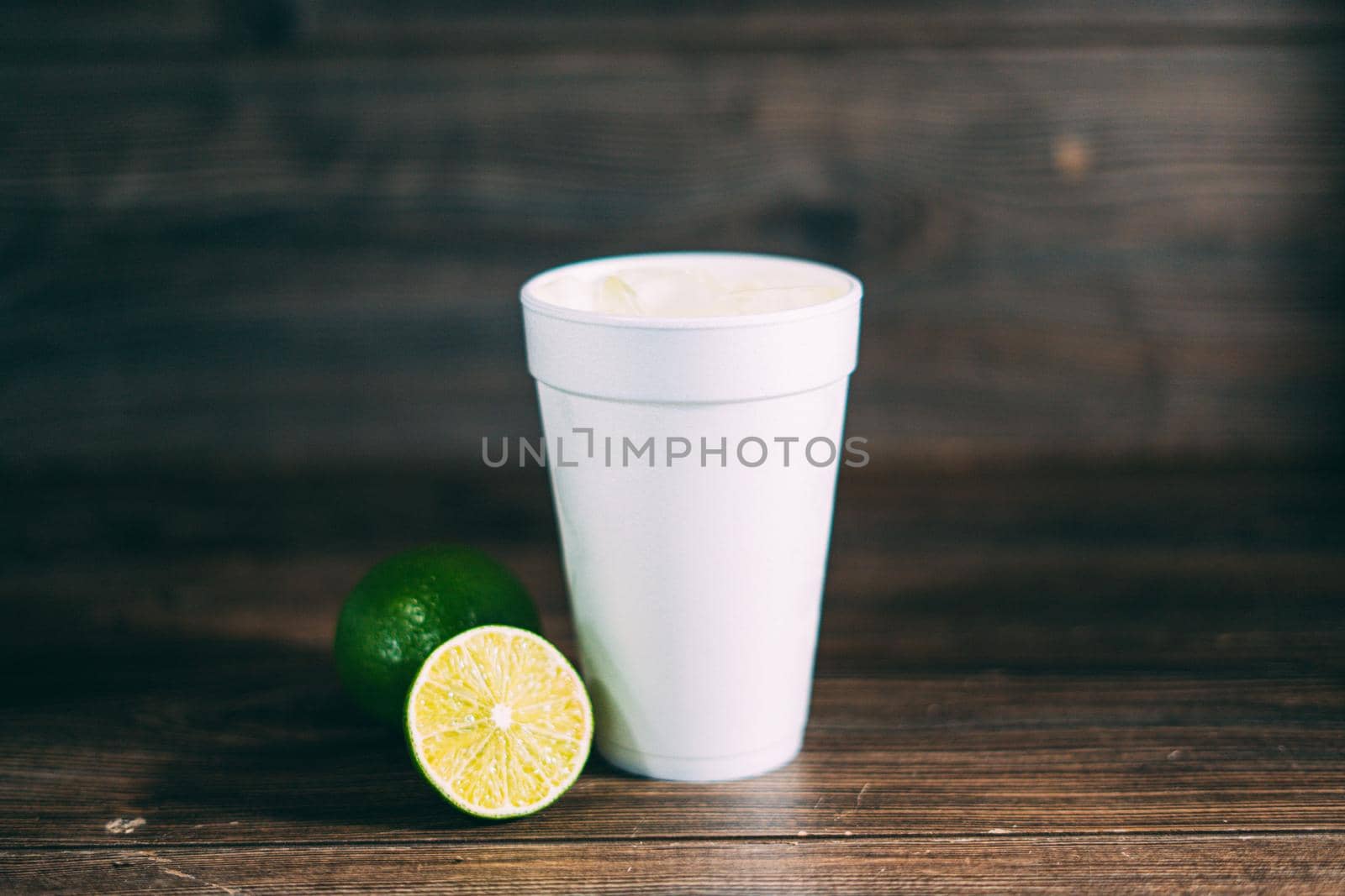 A disposable styrofoam cup and a citrus fruit