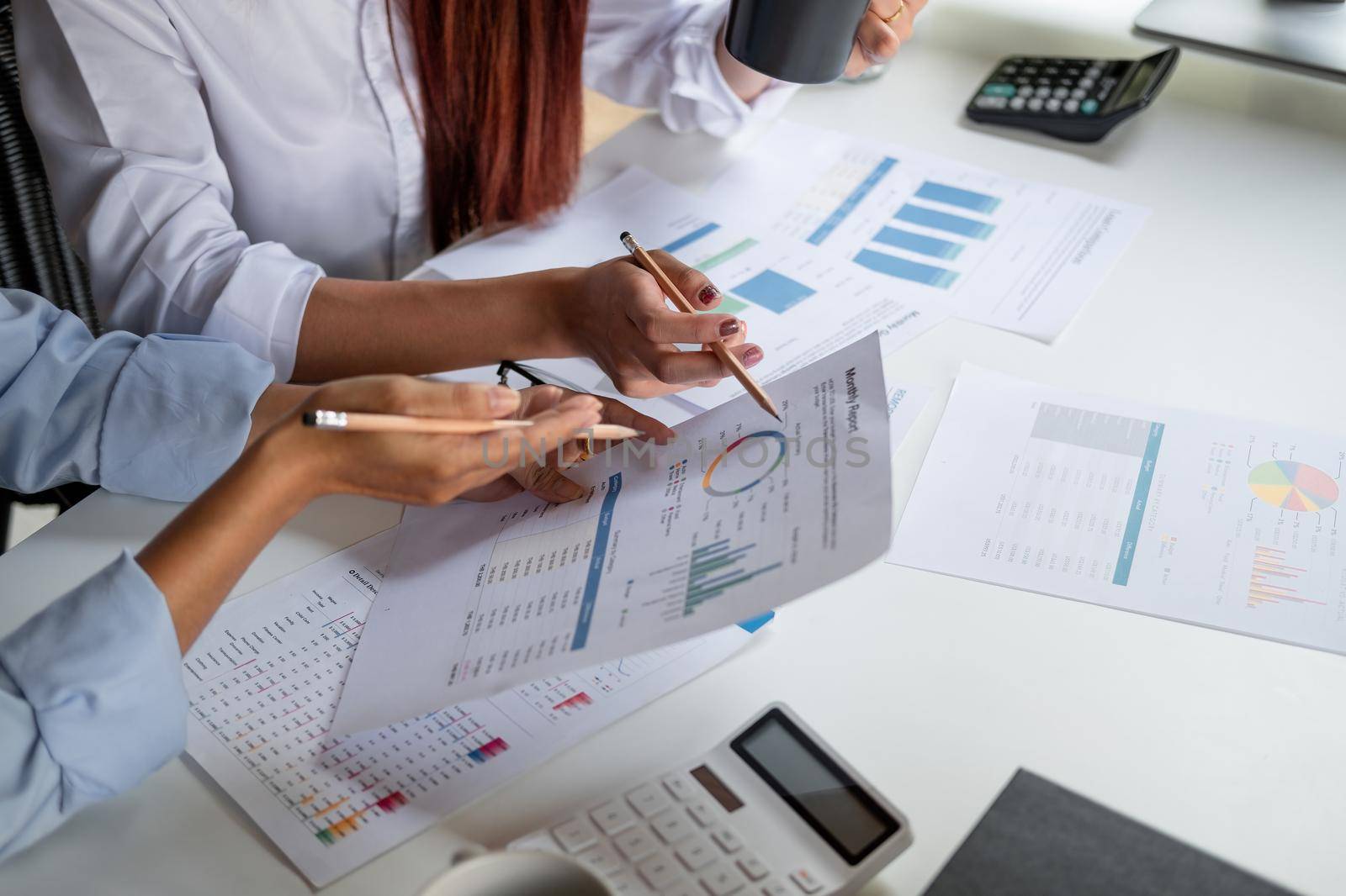 Two colleagues discussing with document data and calculator on desk table. Close up business team analysis and strategy concept.