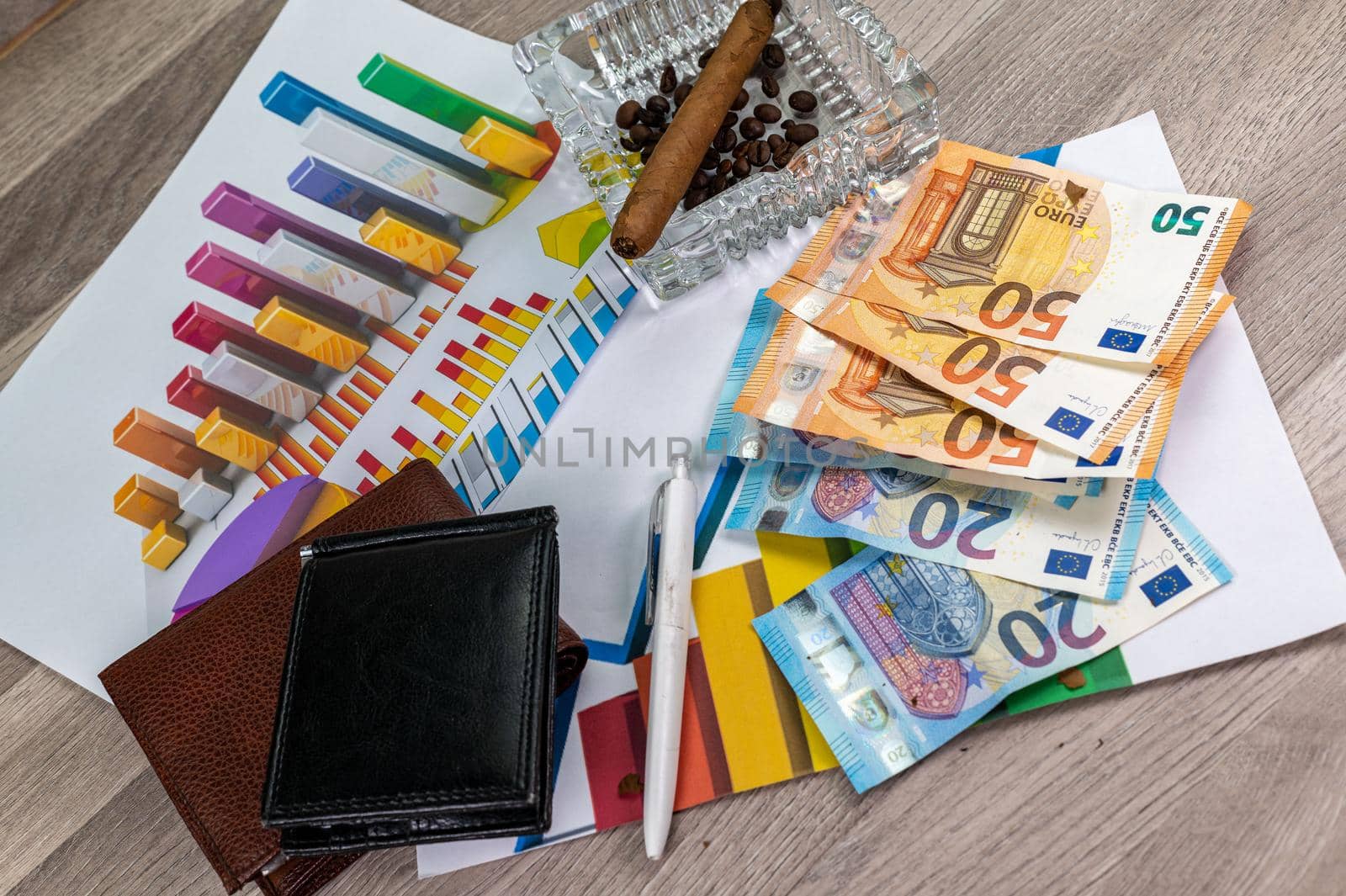 wooden table with 50 and 20 euro banknotes ashtray and cigar with statistics and wallet