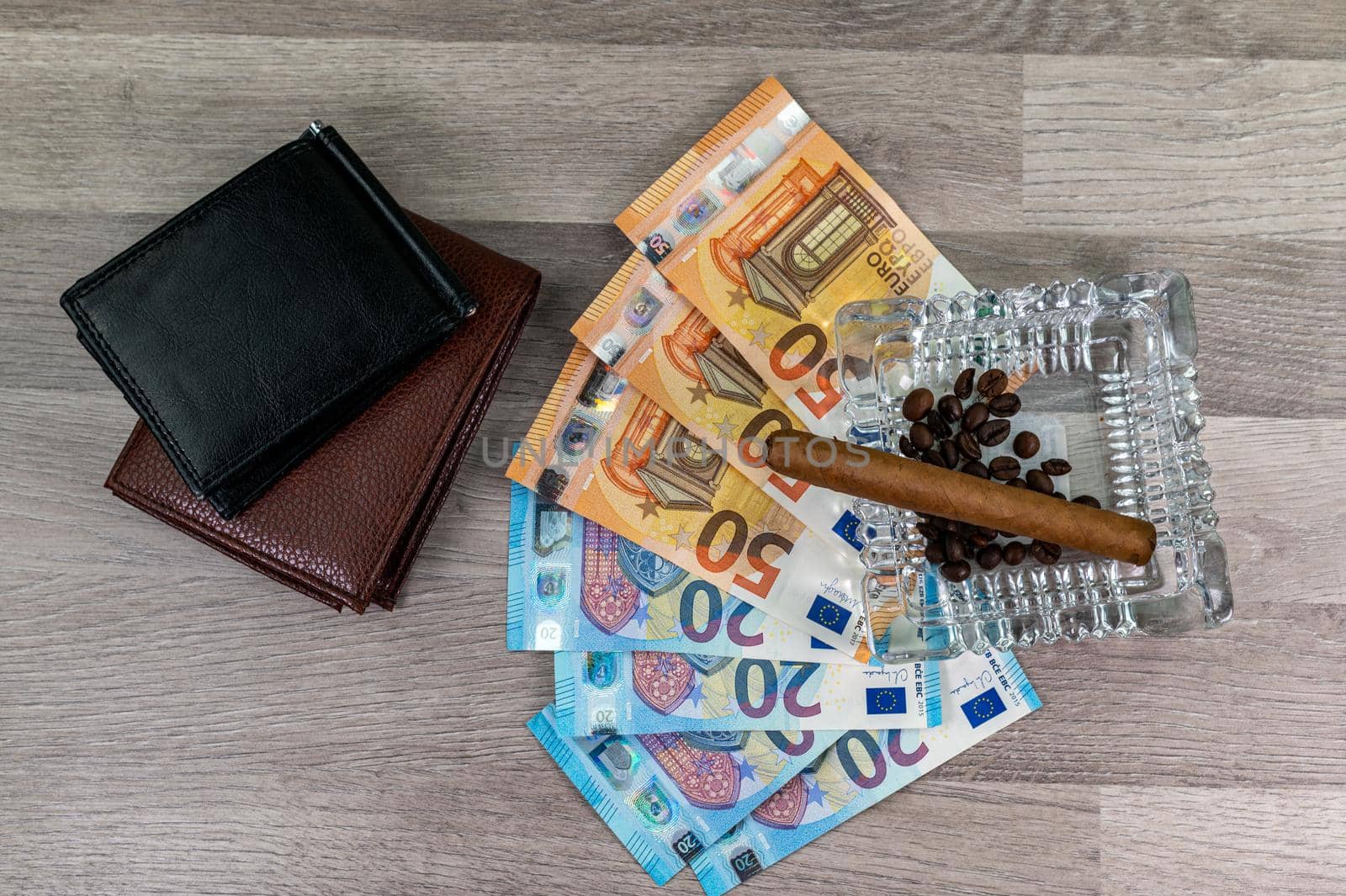 20 and 50 euro banknotes and wallet and cigar on wood background