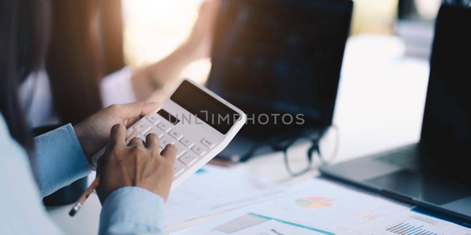 Group businessman hand using calculator to employees to increase productivity.Writing paper on desk.