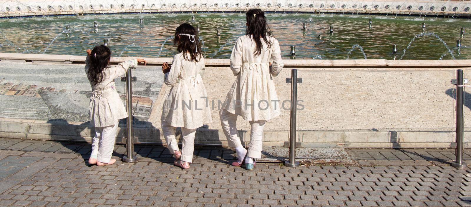 Three little girls by the pool with domes in Istanbul