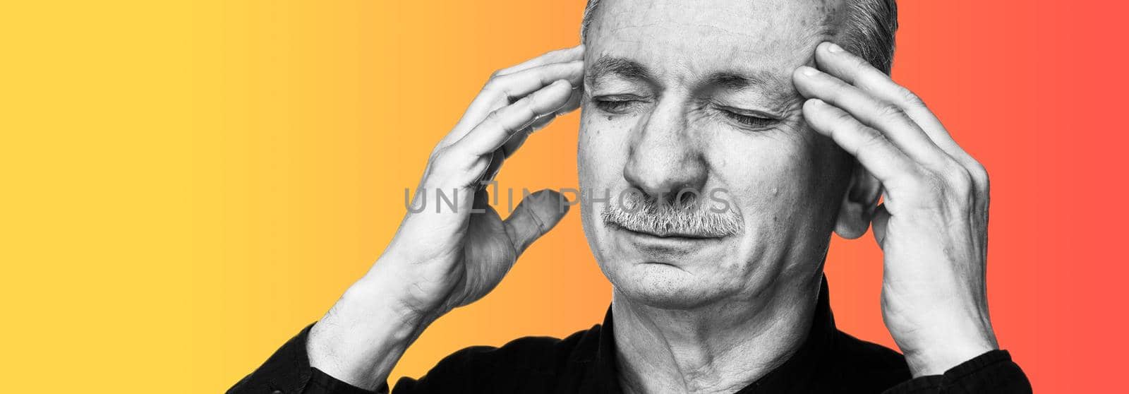 Strong headache. Old man touches his head with his hands and feeling tired and headache. Health care concept. BW image of old man suffering from a headache isolated on background with copy space.