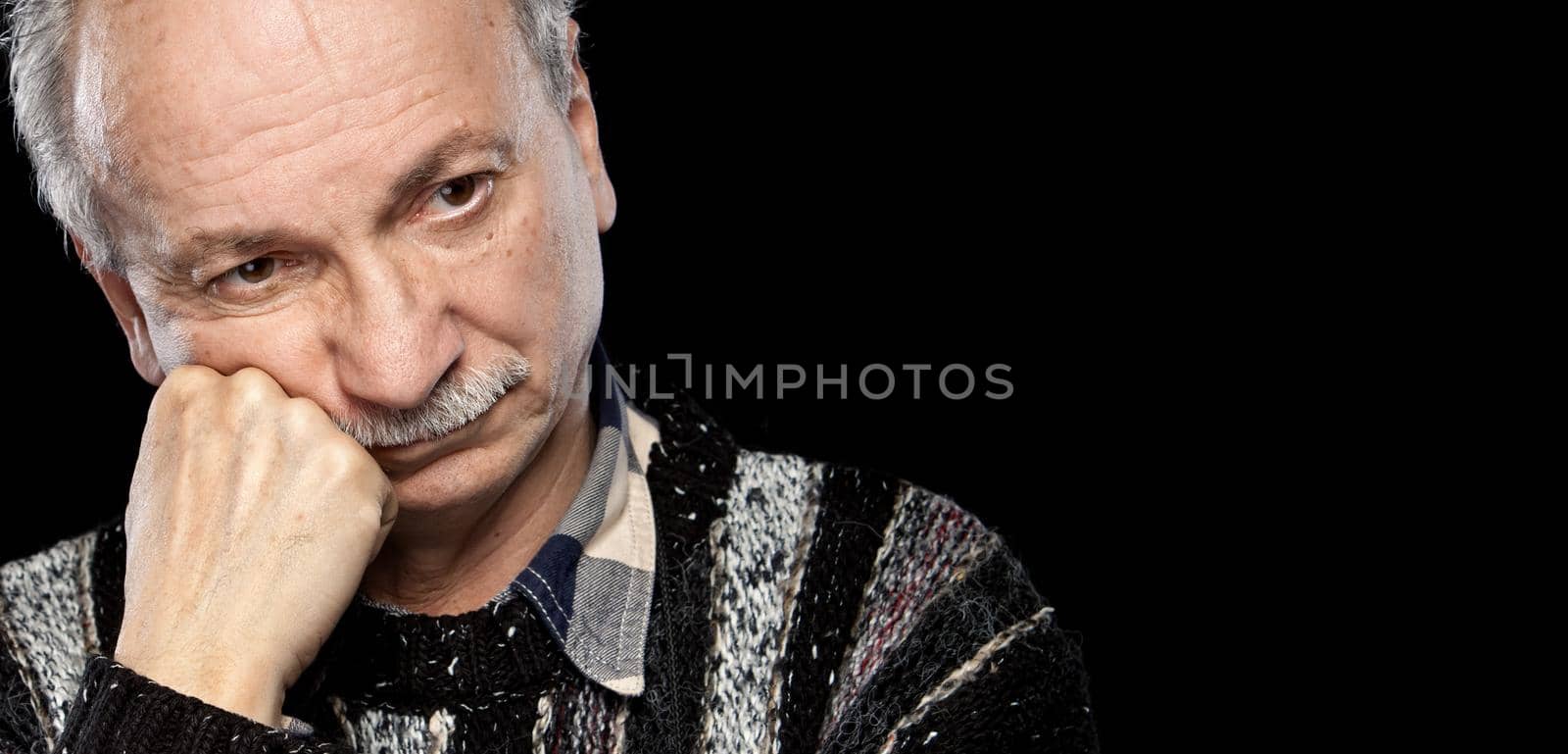 Handsome senior man with a tired expression isolated on black with copy-space