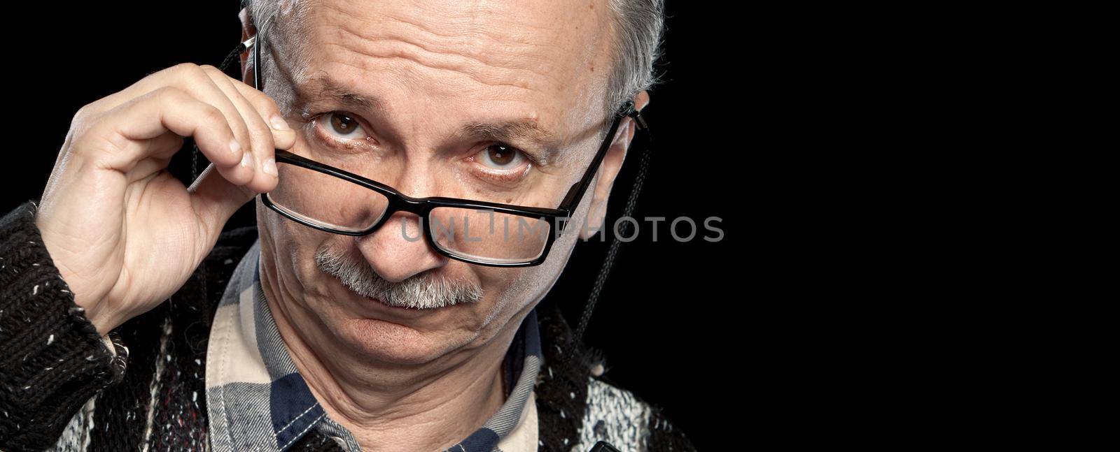 Portrait of a senior man with glasses on black background with copy-space
