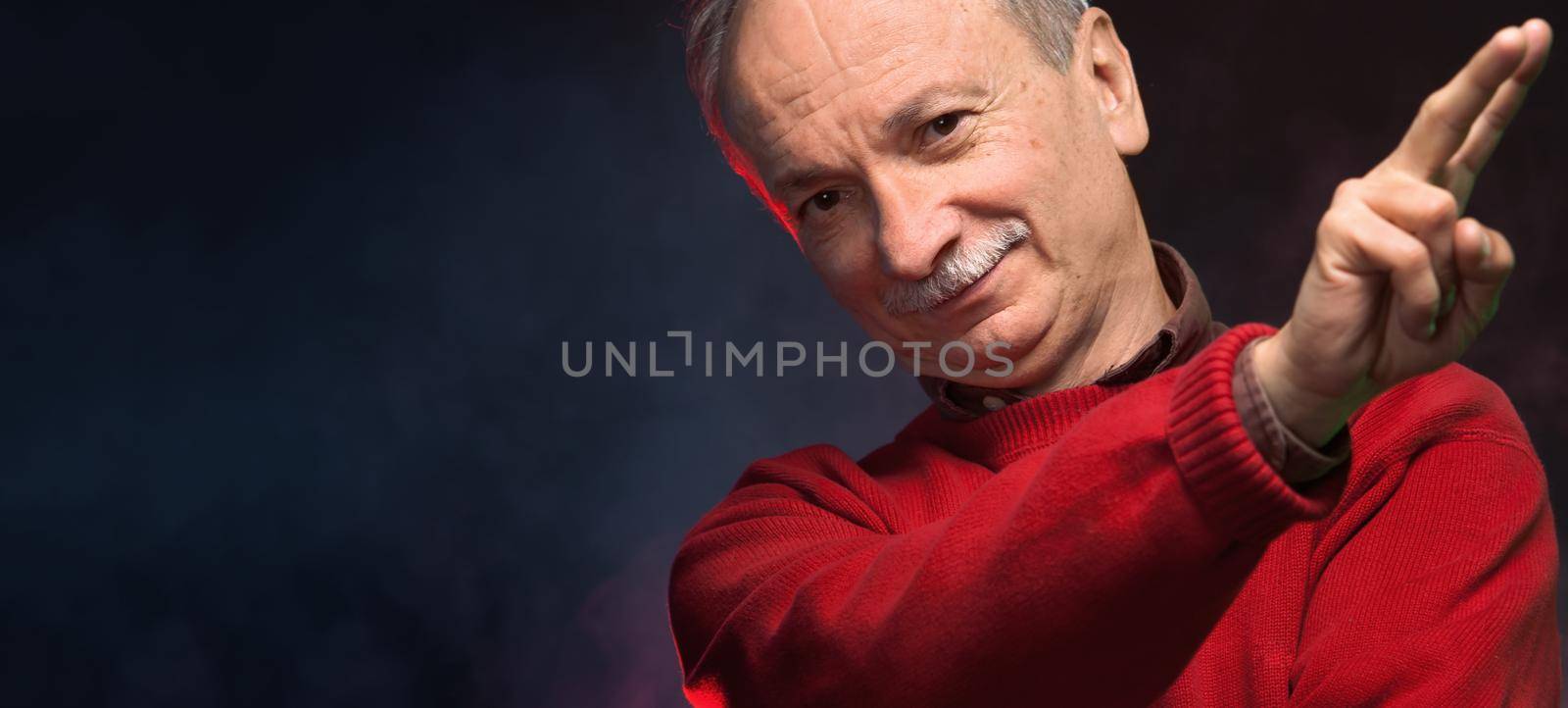 Close-up portrait of an elderly man gesturing at a blurred background