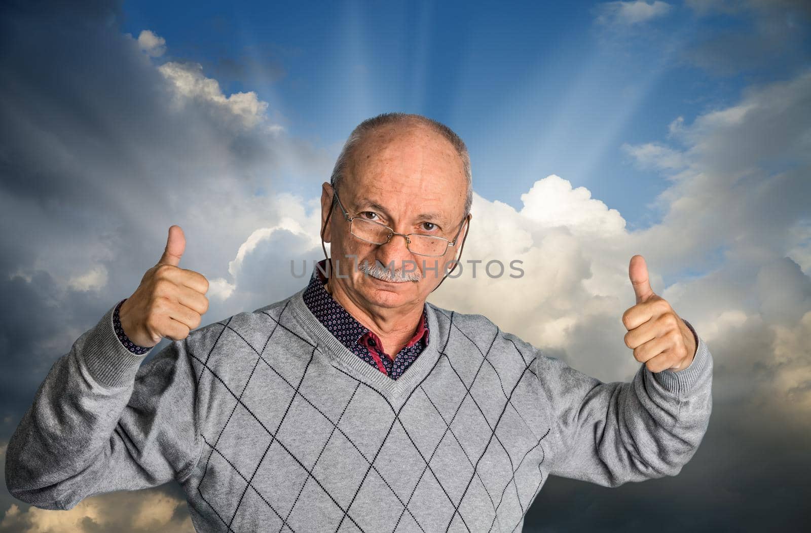Free happy retired senior man with glasses enjoying the outdoors with cloudy sky and shows thumb up.