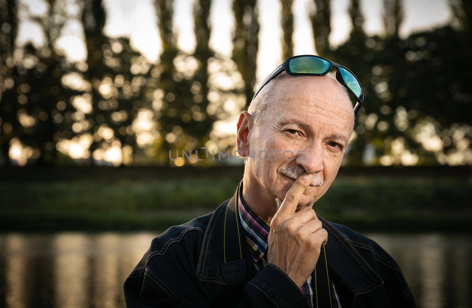 Life style concept. Old man. Portrait of a wise, skeptical and tired of life elderly man on a natural background